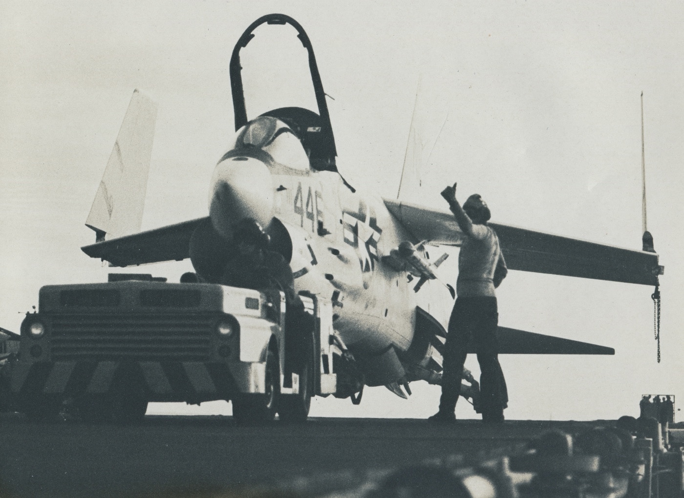 In this photo, U.S. Navy sailors reposition an F-8 Crusader on the deck of an aircraft carrier. The Crusader's prominent turbojet engine is plainly visible. Also shown are the variable-incidence wings that made the plane flyable in naval aviation. The planes are memorialized in the National Air and Space Museum and the USS Hornet museum. 