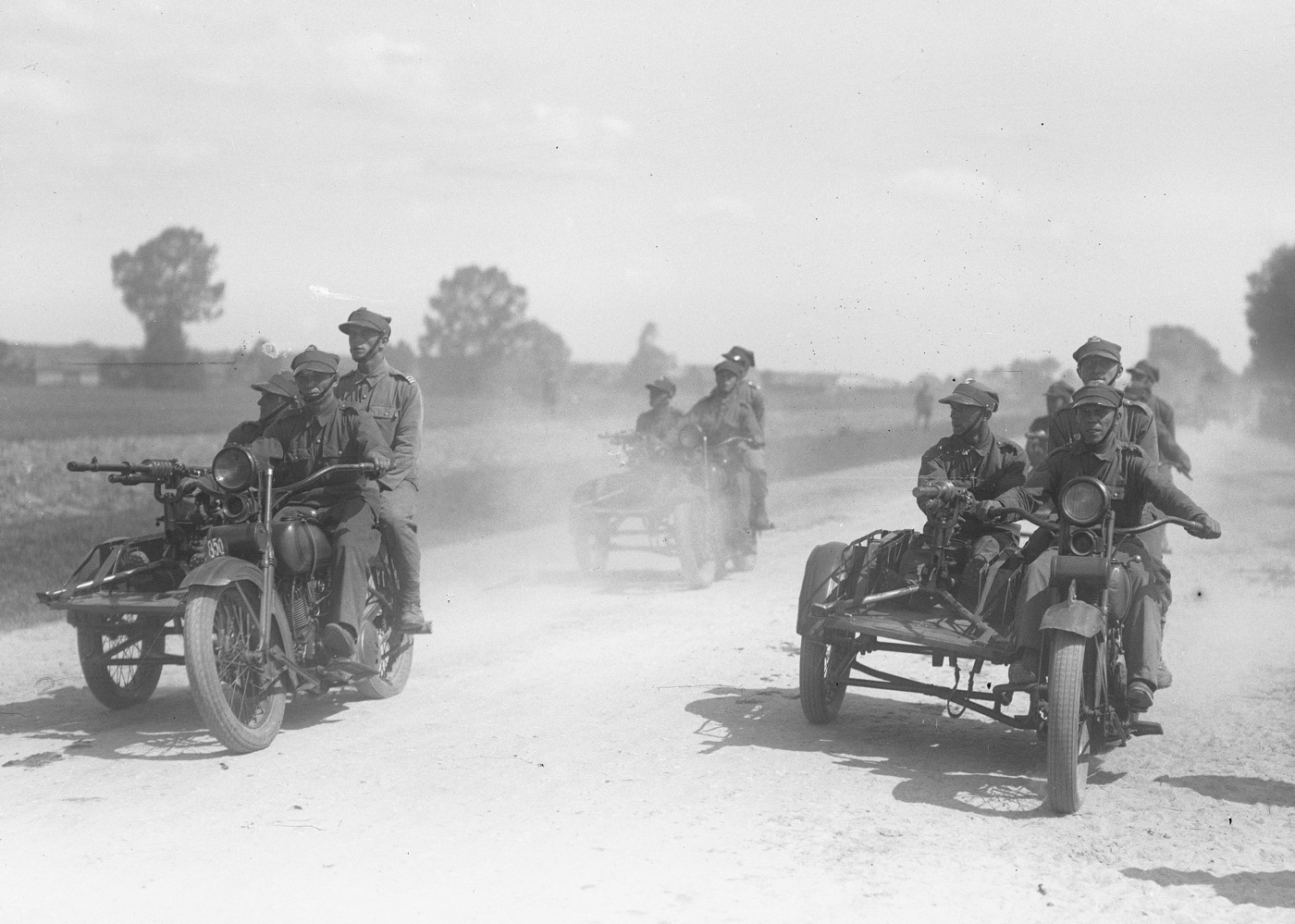 In this photo, Polish soldiers drive three Haley Davidson motorcycles down a dusty road. Each of the bikes has a flatbed style sidecar with a Hotchkiss machine gun model 1914 mounted to it. While the Hotchkiss modèle 1914 was used by the French, other allied countries also employed it. This photo was taken during the Interwar years.