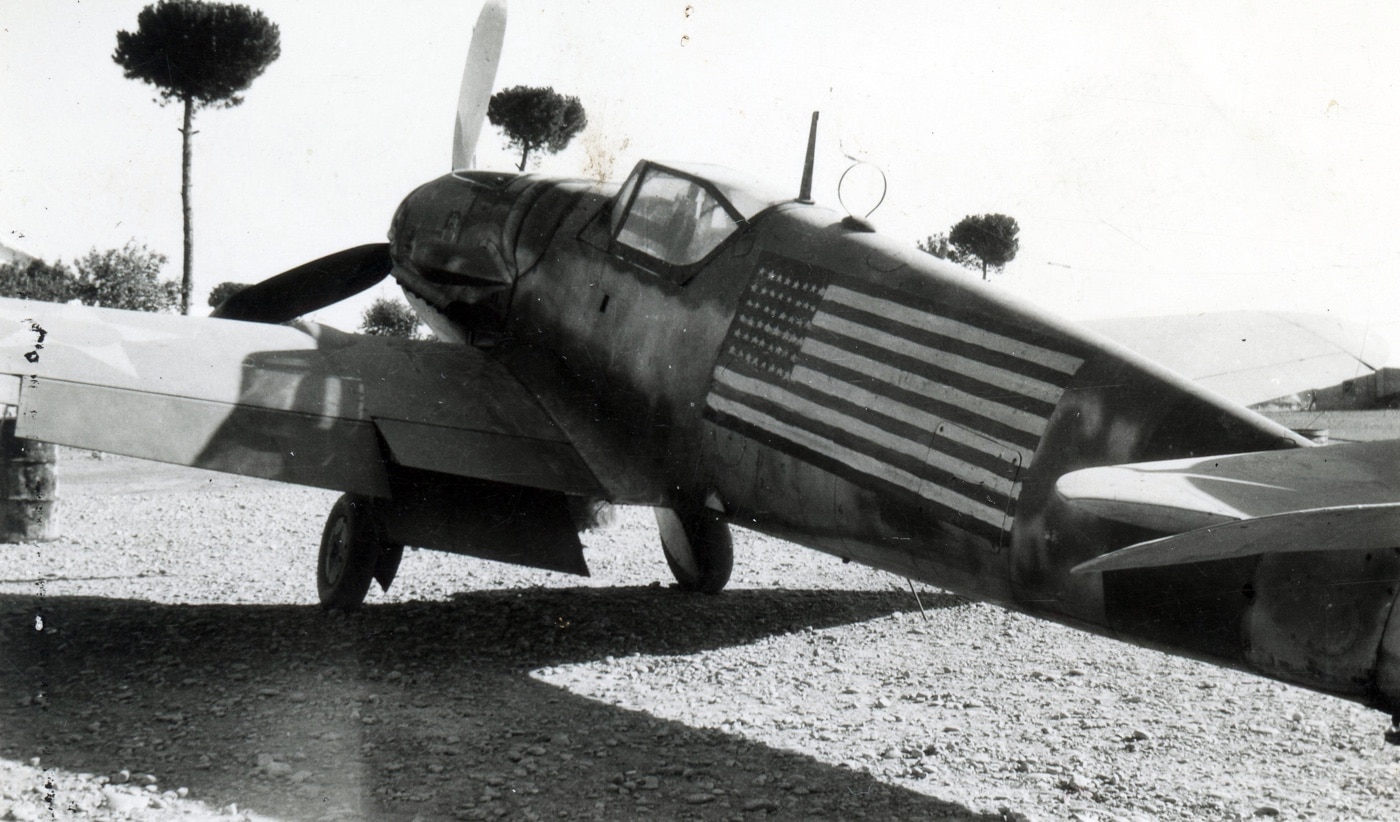 This is a photo of the Romanian Bf 109 that was used to rescue Lt. Col. Gunn. The hand painted American flag of the United States is on the body of the plane. The flag painted on the side by the fighter pilot who flew the plane wanted to arrange for the USAF and OSS to meet them after landing on arrival at the US airbase. This is the stuff of legend.