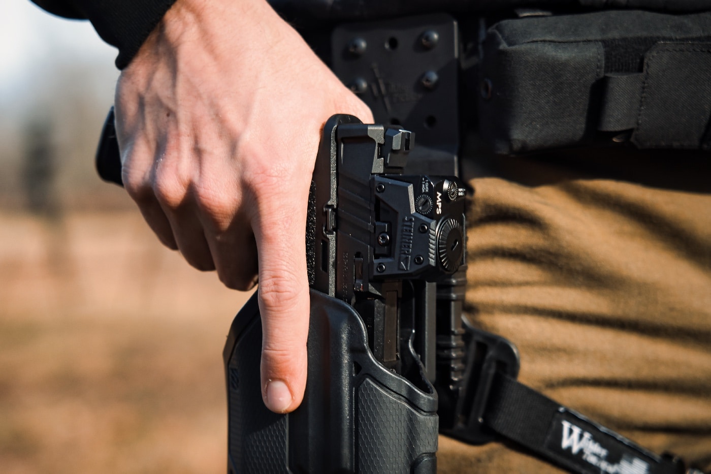 Shown here is the author testing the optic with a Blackhawk holster designed for police and military duty use. You can see the clearance that the rig provides for a red dot sight. The Safariland rig offers a similar fit and clearance. The MPS is powered by a battery that is top mounted which is perfect for an optic from the pistol for fast target or sight acquisition. 