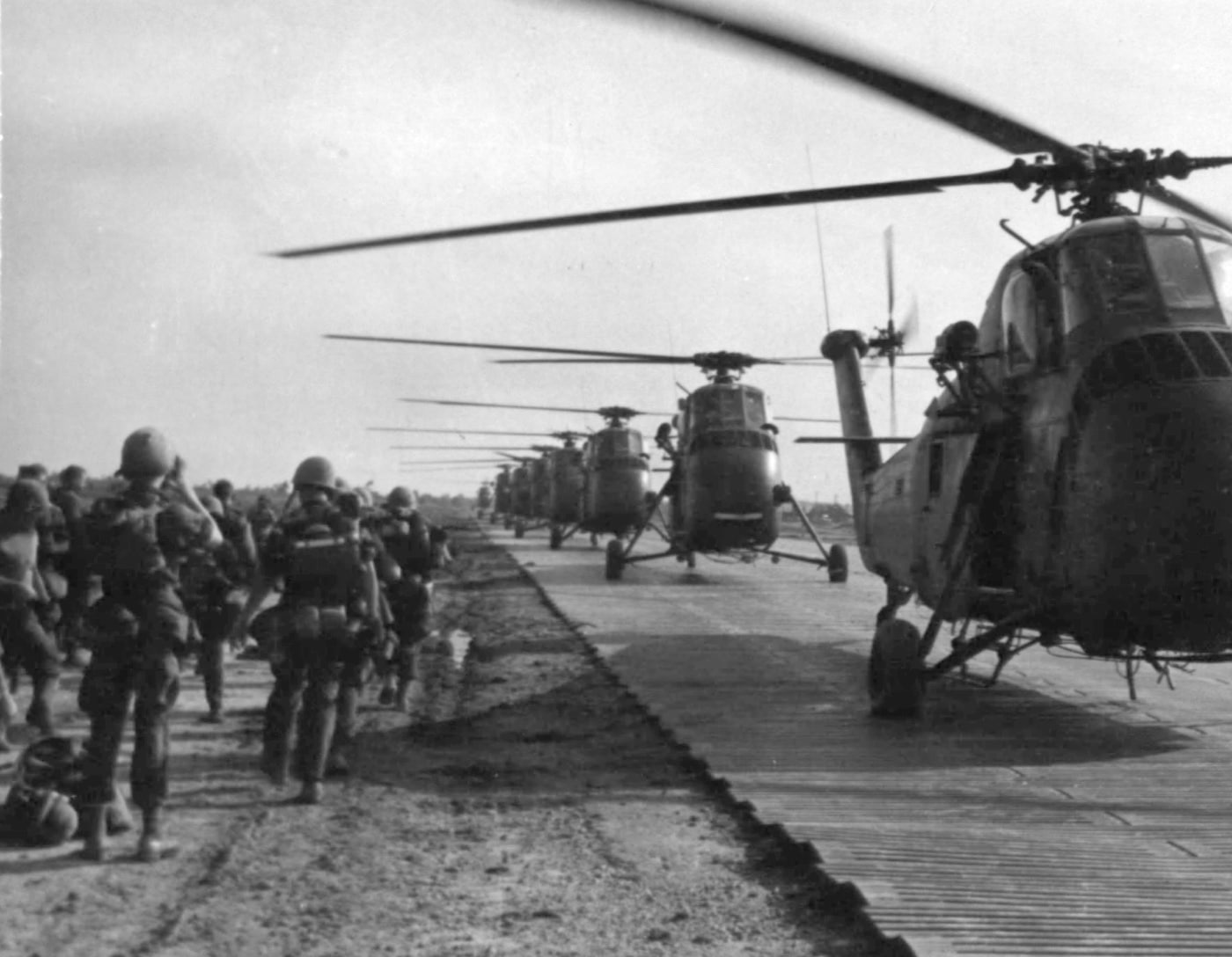 In this historical photo, we see a long line of UH-34 helicopters lined up on an improvised landing surface to transport Marine infantry on a search and destroy mission near Da Nang air base in Vietnam. Marine aviation units used the Sikorsky UH-34D Seahorse extensively for utility transport, medical evacuation and troop movements. 