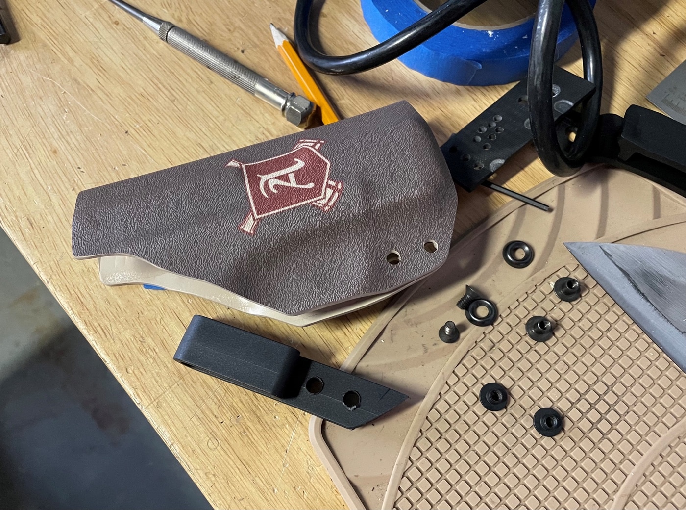 In this photo, the author is preparing to attach the belt clip to his home made holster. There are different attachment methods, but one of the most popular is with Chicago screws. In the pic you can see the eyelets that are pressed into the holes. The screws then go through them to secure the rear of the holster. Some people choose to use rivets instead of screws. These can work, but you loose the ability to adjust the tension and gun retention. If you rivet it too tight, you have no viable way to loosen it. Screws can be had in different colors to match the Kydex material you have selected.