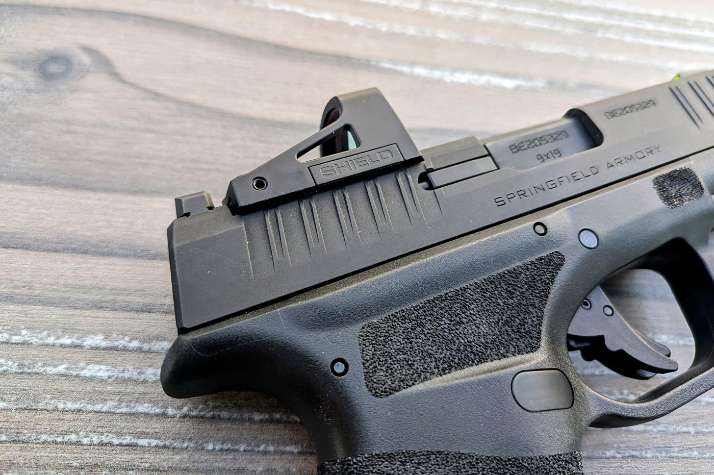 In this photo, you can see the battery compartment on the right side of the Shield RMSd. You can swap batteries without removing the optic from the pistol. The brightness adjustment on the RMSd is another standout feature. It automatically adjusts to the ambient light conditions. This range includes a lowest setting compatible with night vision devices and a highest setting that remains visible against the sky in bright daylight. This adaptability is crucial for a concealed carry optic, as it ensures optimal visibility in all lighting conditions.