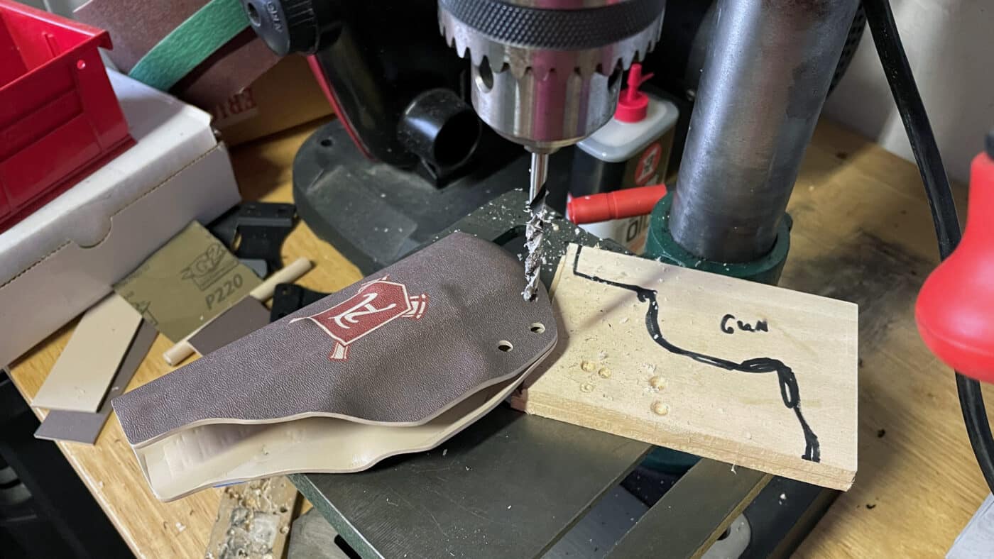 In this photo, the author is using a drill press to make precise holes in the Kydex holster he is making. The holes are where he will attach the belt clip for concealed carry. It's relatively easy to make Kydex holsters using some simple tools, a heat gun and a mold. Kydex is far easier to work with than leather.