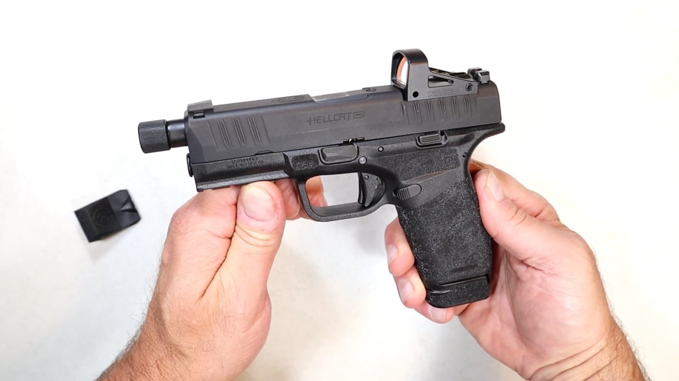 The author handles the Hellcat Pro pistol in this photo. Mounted on the slide is the new Shield RMSd red dot sight that he is reviewing in this article. Its convenient quick-release battery compartment, accessible from the side, allows for hassle-free battery replacement without the need to remove the sight from the firearm.