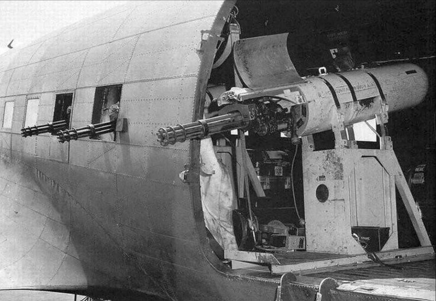 In this photograph we see a GAU-2/A minigun on an early prototype mount in the doorway of a AC-47 gunship. Early mounts like this one were improvised by crews in the field. The M134 Minigun is an American 7.62×51mm NATO six-barrel rotary machine gun with a high rate of fire. It features a Gatling-style rotating barrel assembly with an external power source, normally an electric motor. It was designed and manufactured by the General Electric company.