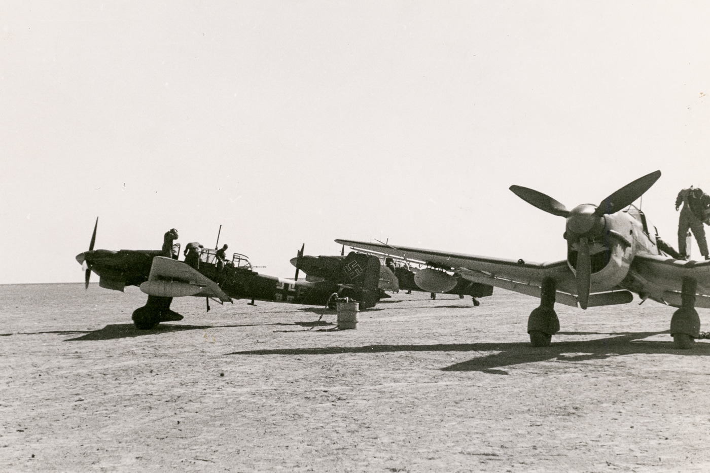 In this digital image, we see several Stukas on the flight line that are being prepared for combat in France. You can see the rear gunner entering the cockpit of one aircraft. His mission was to keep the RAF pilots off of the plane when the Messerschmitt Bf 109 fighters were unavailable. When running a dive-bomb mission, the planes were particularly vulnerable to hits on the fuselage — a point made by Von Richthofen during pre-war strategy sessions.