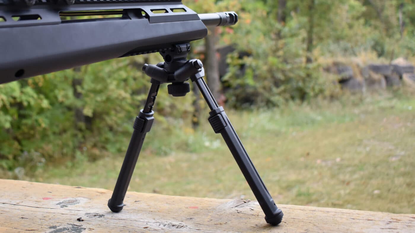 This is a photo of the author using the Magpul bipod attached to a SAINT rifle. She has it resting on a shooting bench.