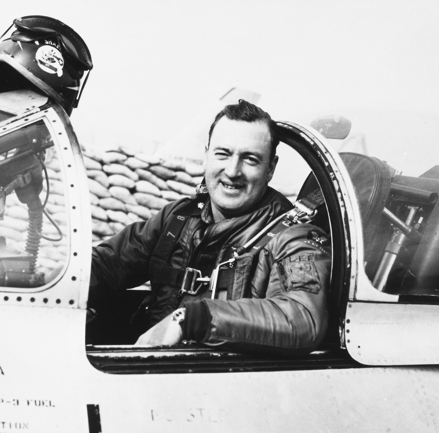 In this photo, Maj William Shaeffer, a Korean War pilot, smiles at the camera while sitting in the cockpit of his F-86 plane. 