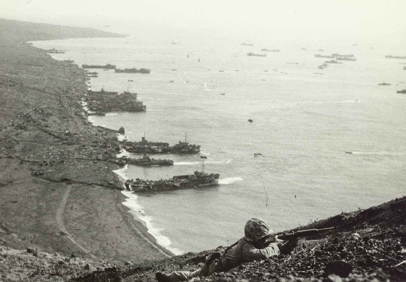 In this digital photograph, a lone Marine holds a M1 Garand rifle in a prone position as he protects the flank of a United States Marine Corps patrol making its way up the hill behind him. The Battle of Iwo Jima was largely the plan of United States Navy Admiral Chester W. Nimitz and carried out by the 4th Marine Division and 5th Marine Division. 