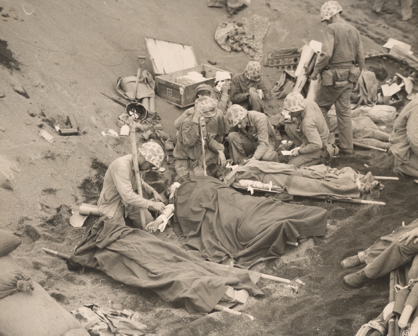 Navy corpsmen administer to wounded Marines at an aid station established in a gully on Iwo Jima. Image: Warrant Officer Obie Newcomb/U.S. Marine Corps
