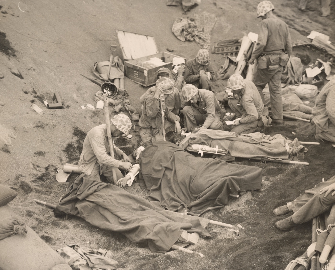 Navy corpsmen administer to wounded Marines at an aid station established in a gully on Iwo Jima. Image: Warrant Officer Obie Newcomb/U.S. Marine Corps