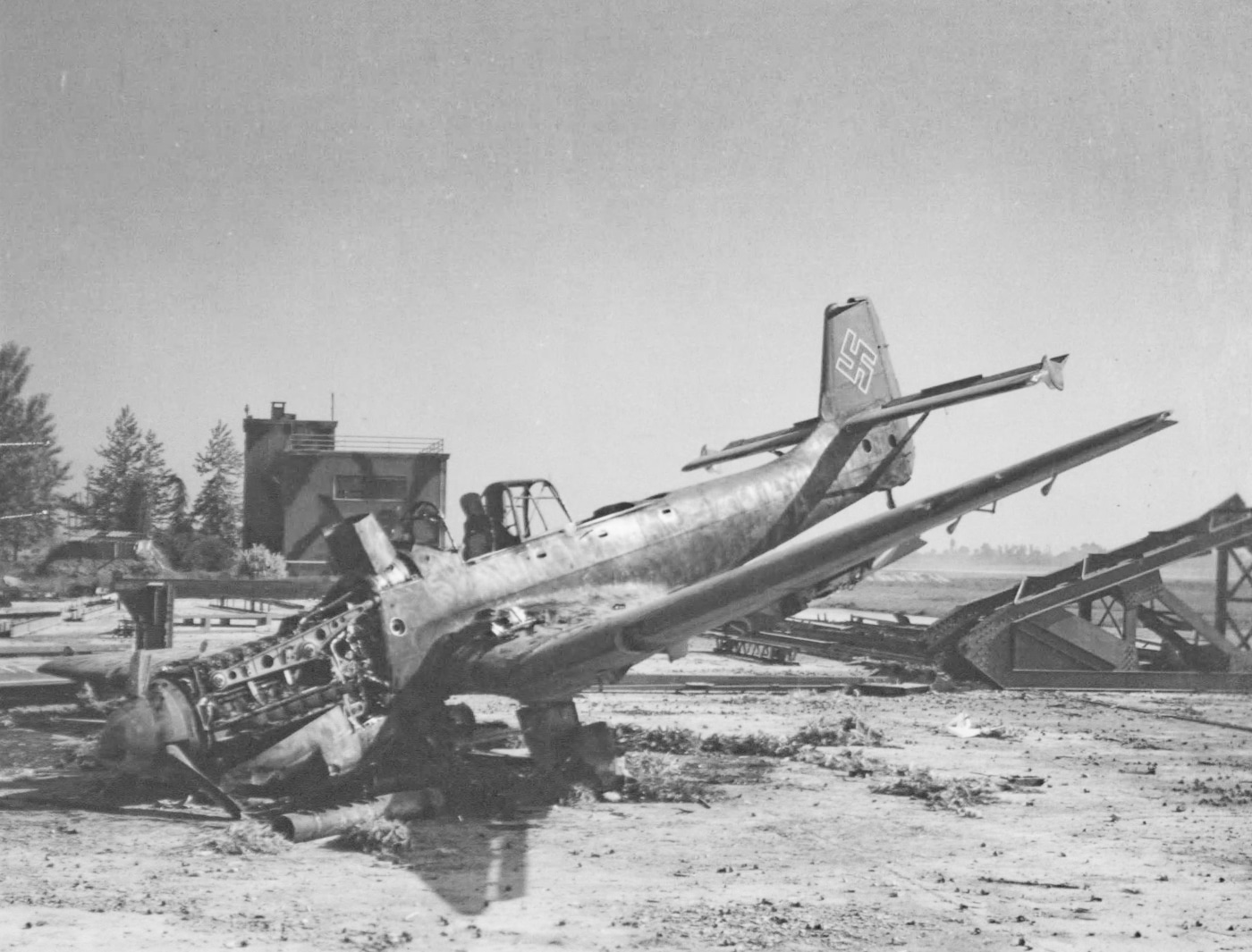In this image, we see a heavily damaged Ju 87 on the ground. The airfield had been hit by a B-24 raid late in World War 2. The Consolidated B-24 Liberator is an American heavy bomber, designed by Consolidated Aircraft of San Diego, California. It was known within the company as the Model 32, and some initial production aircraft were laid down as export models designated as various LB-30s, in the Land Bomber design category.