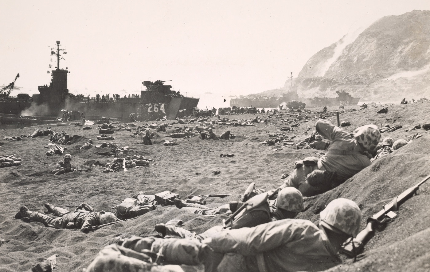 In this photo, we see United States Marines on the black sand beach of Iwo Jima. Iwo Jima was part of the leapfrogging strategy of the United State in World War 2. Leapfrogging, also known as island hopping, was an amphibious military strategy employed by the Allies in the Pacific War against the Empire of Japan during World War II.