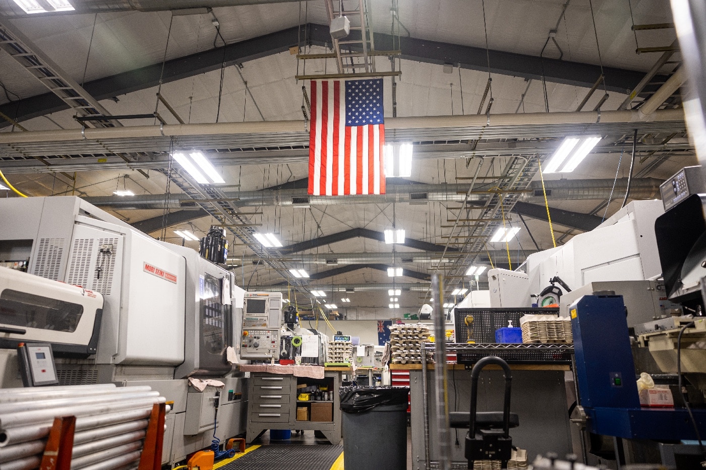 In this digital image, we see CNC machines, metal working tools and a United States of America flag. 