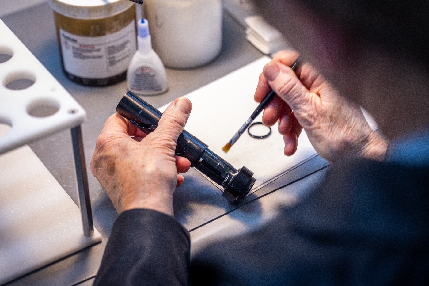 In this photo, an employee is shown cleaning the optics of a scope with a small brush.