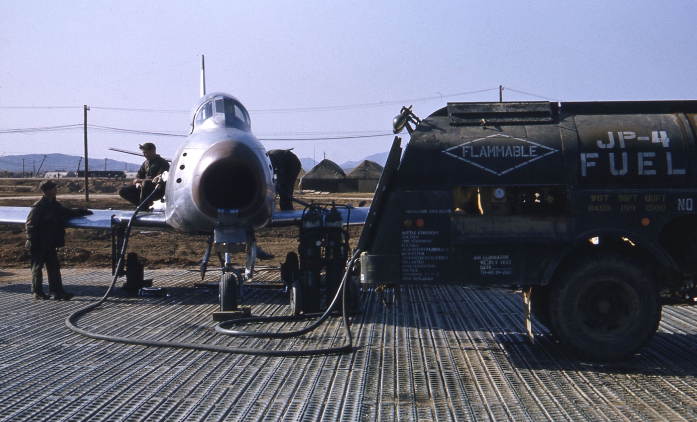 In this image, we see the ground crew fueling an F-86 airplane somewhere in South Korea. These jets ran on JP-4, a jet fuel standard for the U.S. Air Force starting in 1951 and running through 1995. JP-4 had a lower flashpoint than JP-1 — meaning it was more dangerous to work with, but it was much easier to produce which made it more available. It was essentially a blend of gasoline and kerosene. 
