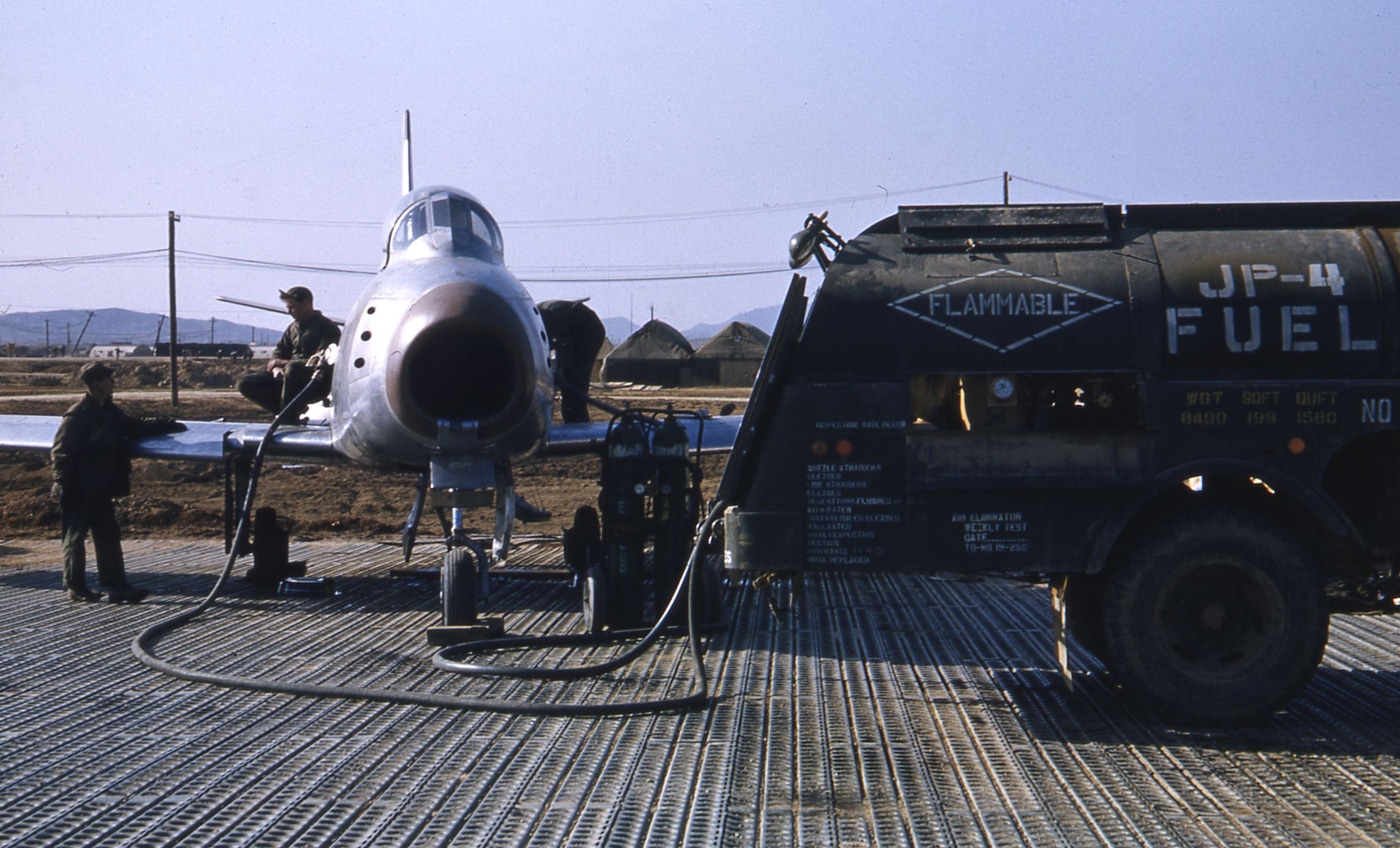 In this image, we see the ground crew fueling an F-86 airplane somewhere in South Korea. These jets ran on JP-4, a jet fuel standard for the U.S. Air Force starting in 1951 and running through 1995. JP-4 had a lower flashpoint than JP-1 - meaning it was more dangerous to work with, but it was much easier to produce which made it more available. It was essentially a blend of gasoline and kerosene. 