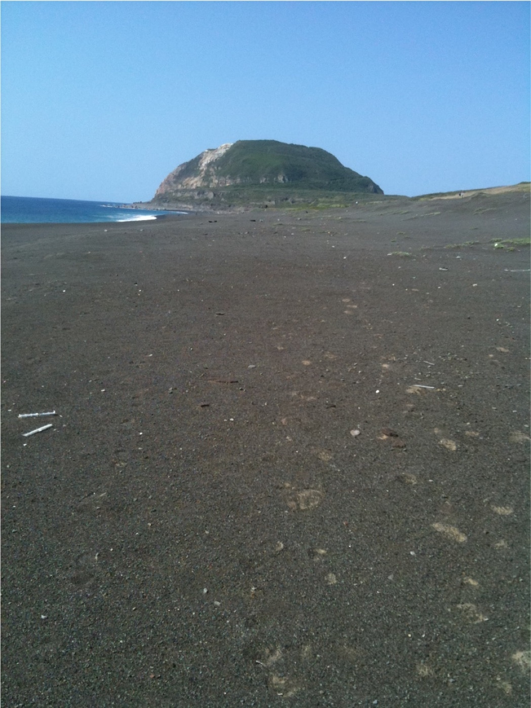 In this photo, we can see the black sand of the Iwo Jima beaches today. Iwo Jima and Okinawa were two bloody battles necessary in the Pacific War. Lessons learned on the island of Iwo Jima were later applied to the preparations for the invasion and Battle of Okinawa. 