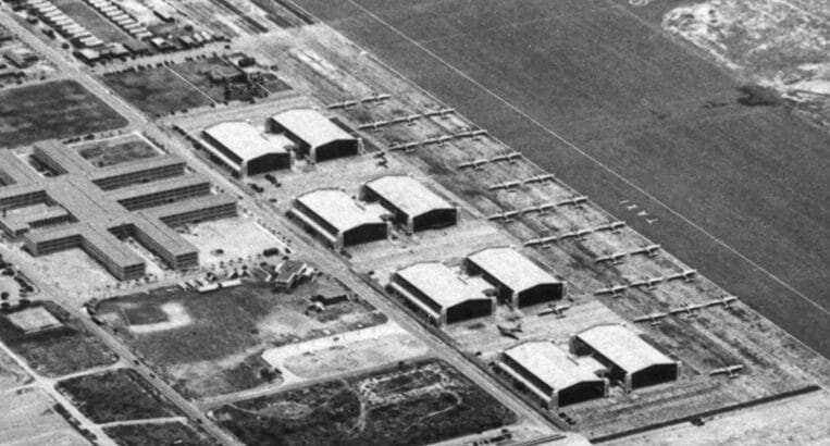 In this digital photo, we see a view of Hickam Field, now known as Hickam Air Force Base in Hawaii, from 4,000' in the air. B-18 bombers are clustered tightly together between the runway and aircraft hangars. Each aircraft pilot would learn to disperse its aircraft when parked on the tarmac. 