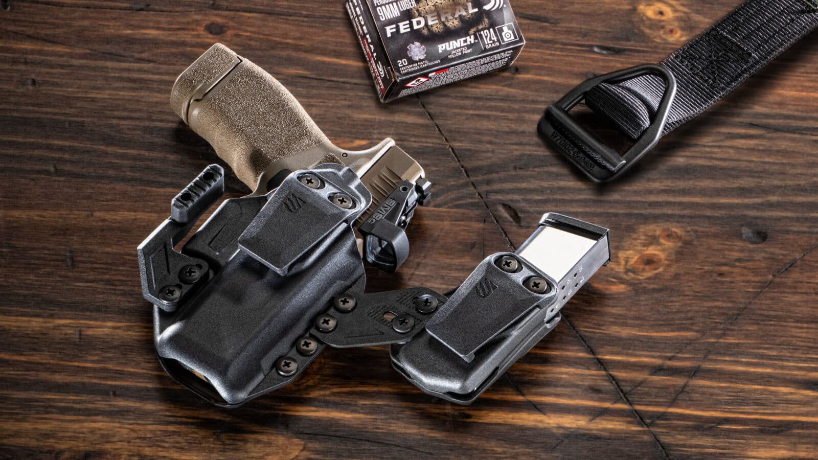 In this photograph, we see the Blackhawk Stache holster reviewed by the author. In addition we see a gun belt, the Springfield Armory Hellcat Pro FDE 9mm pistol and Federal Ammunition in 9x19mm Parabellum.