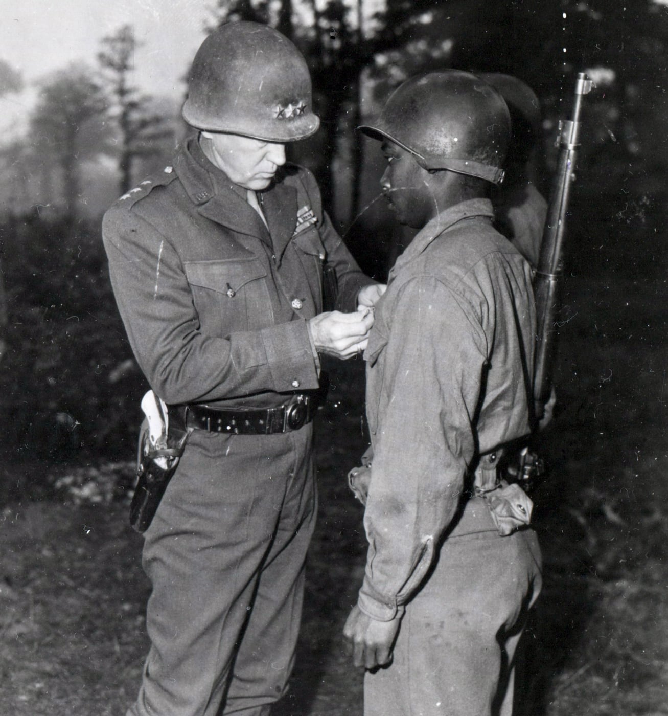 In this image, Gen Patton pins Silver Star on soldier for his heroism in combat.