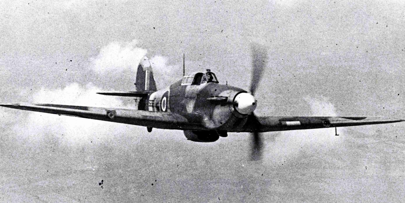 In this black and white photograph, we see a Hawker Hurricane in flight over Great Britain during World War II.