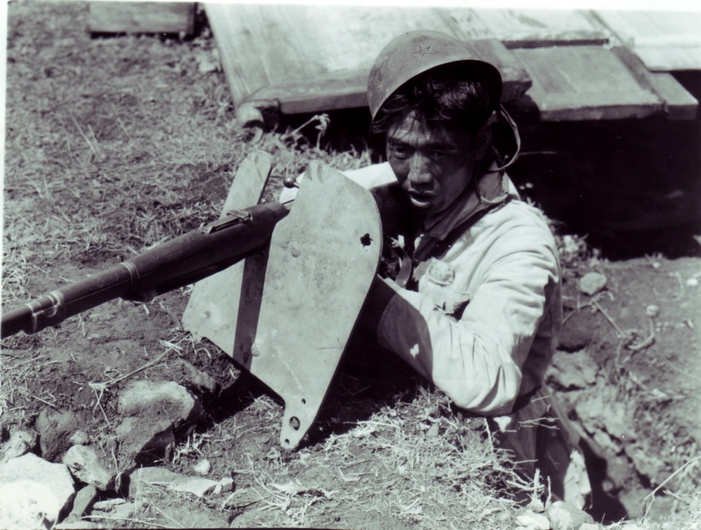 In this rare photo, we see a Chinese soldier of the National Revolutionary Army using an armored shield captured from a member of the Manchukuo Imperial Army which was under the control of the Imperial Japanese Army.  The Manchukuo Imperial Army was the ground force of the military of the Manchukuo, a puppet state established by Imperial Japan in Manchuria, a region of northeastern China.
