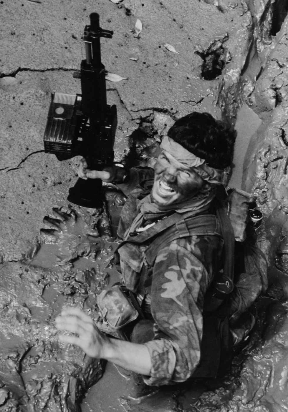This photo shows a Navy SEAL carrying a Stoner 63 through mud on the banks of a river in Vietnam.