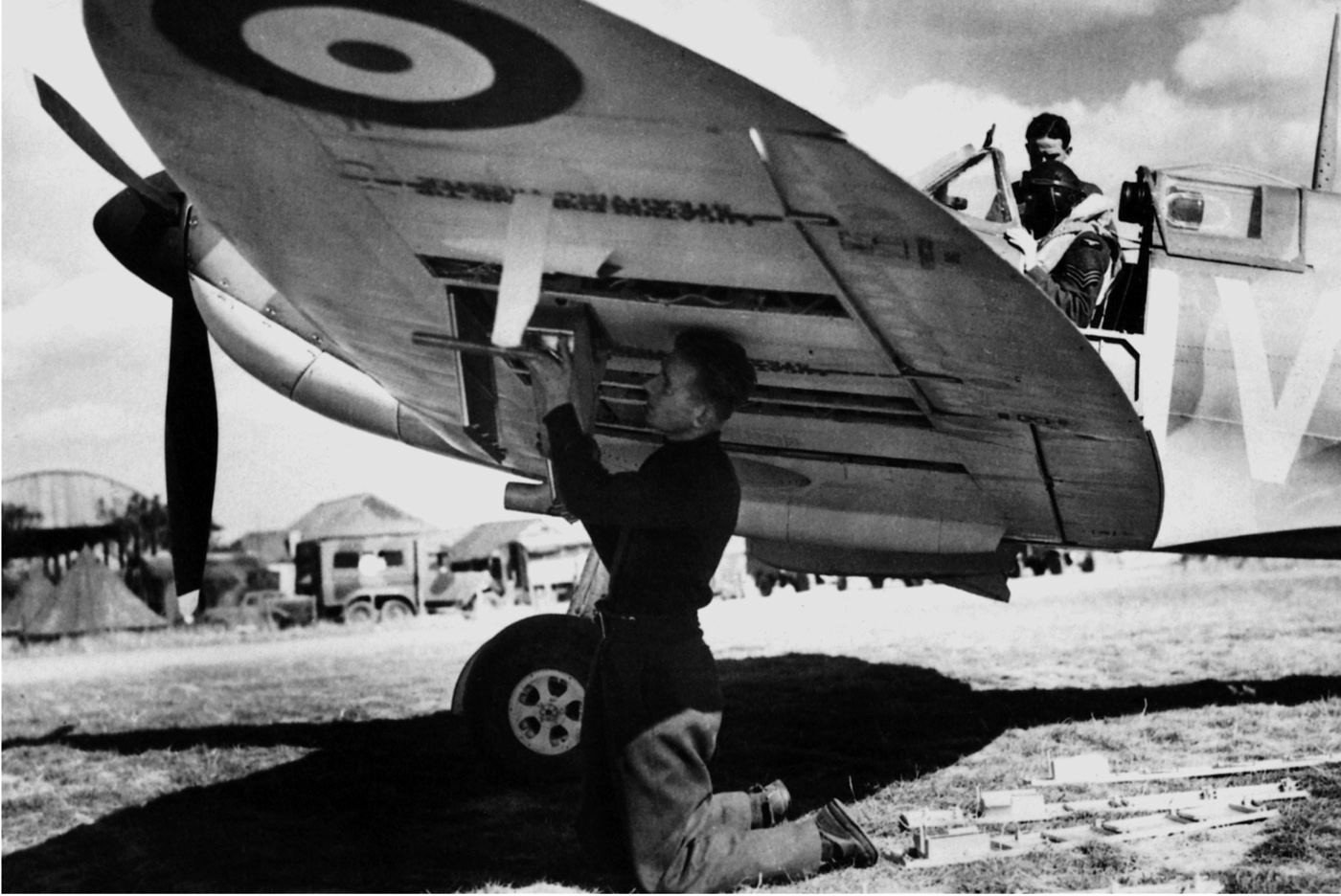 In this photo, a crewman makes adjustments to a Spitfire while reloading ammunition for its guns.
