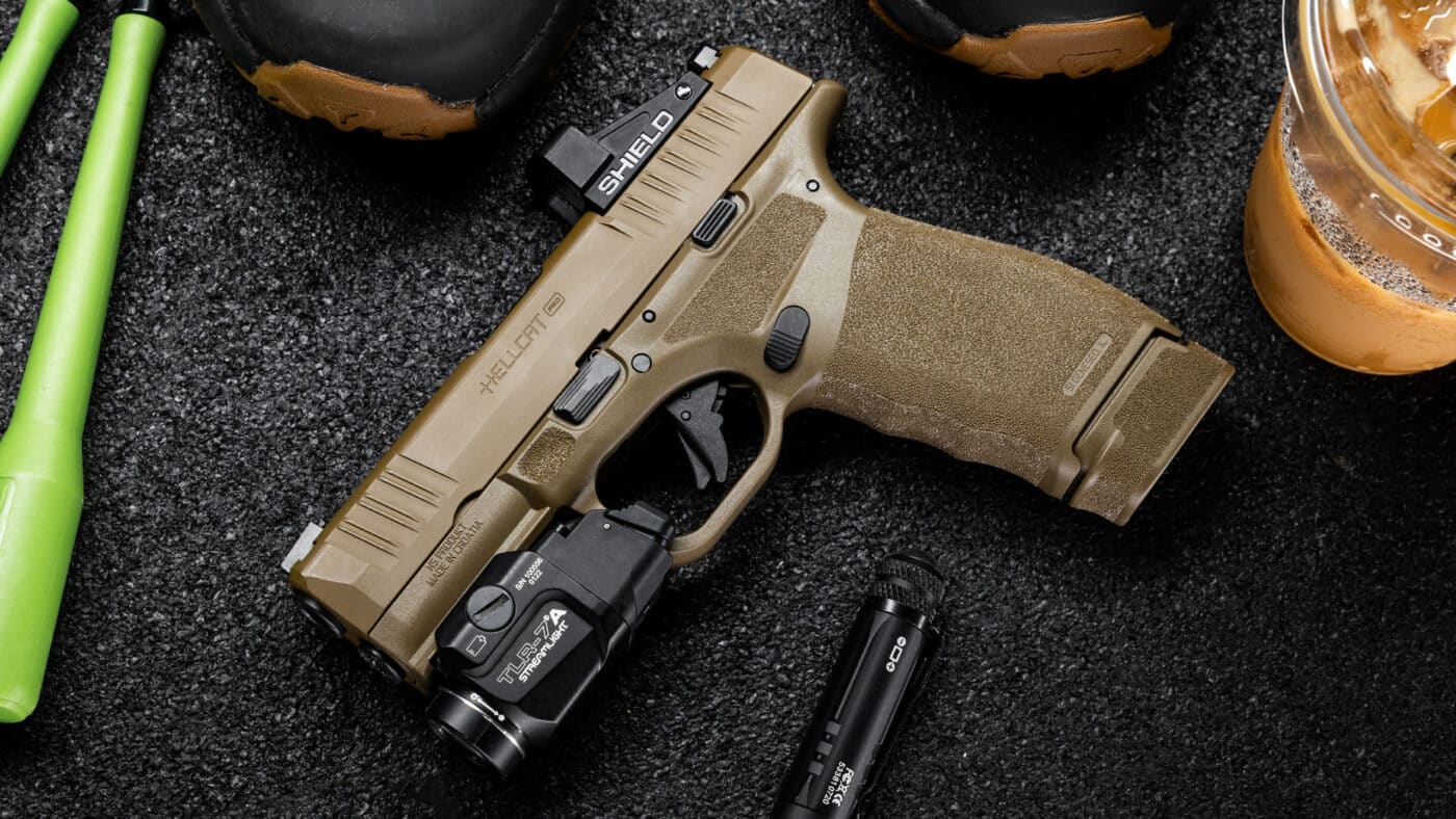 In this photo, we see a Springfield Hellcat Pro with a Desert FDE finish, Streamlight flashlight and red dot sight.