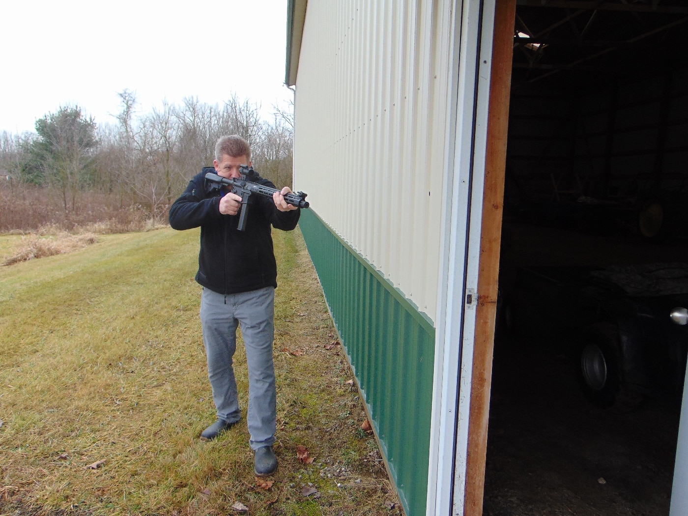 In this photograph, the author demonstrates how to use the pistol caliber carbine in a self-defense situation. His rifle is fitted with a 32-round magazine, a red dot sight, a muzzle brake, rifle stock and adjustable sights. The barrel is 16 inches in length bringing the total length to 35" with the stock fully extended. This provides a good fit for most people and an ideal sight radius when using the stock sights.