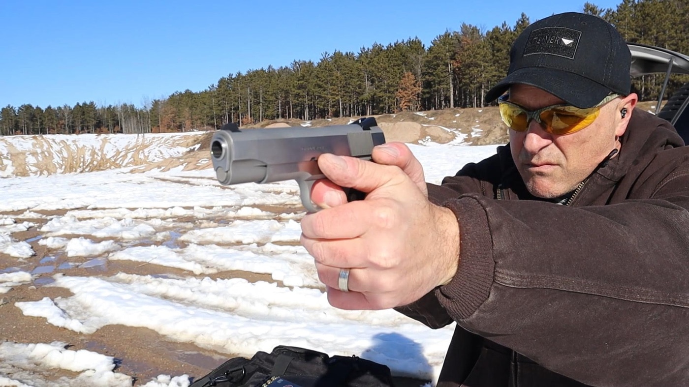 In this photograph, the author is shooting one of the Springfield Armory Garrison 1911 handguns on the shooting range. The range is covered in snow and it very cold.