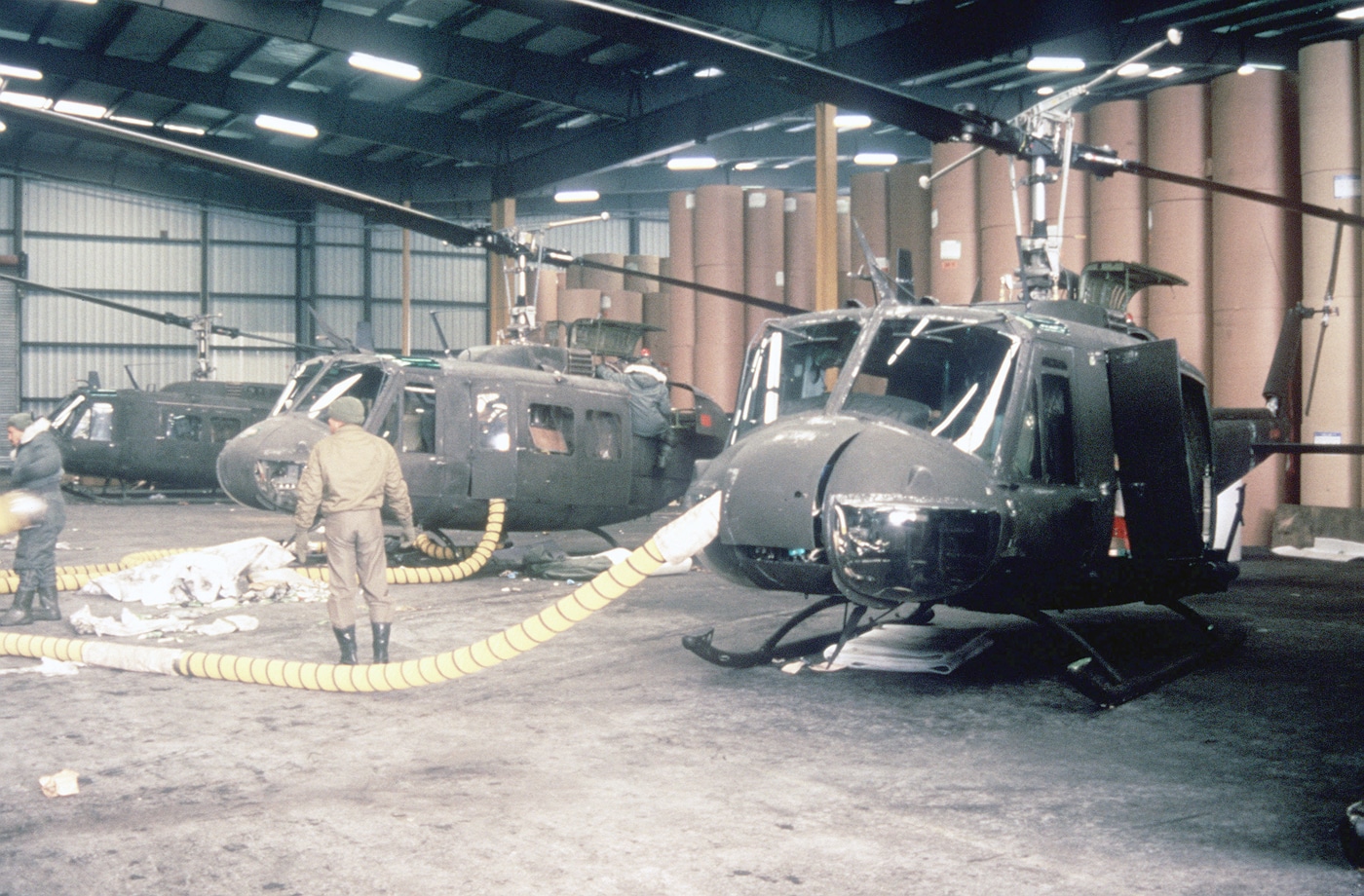 In this photo, we see ground crews unpack and prepare UH-1 Iroquois helicopters for flight in a port warehouse during Exercise REFORGER '85. Exercise Campaign Reforger ("REturn of FORces to GERmany") was an annual military exercise and campaign conducted by NATO during the Cold War.