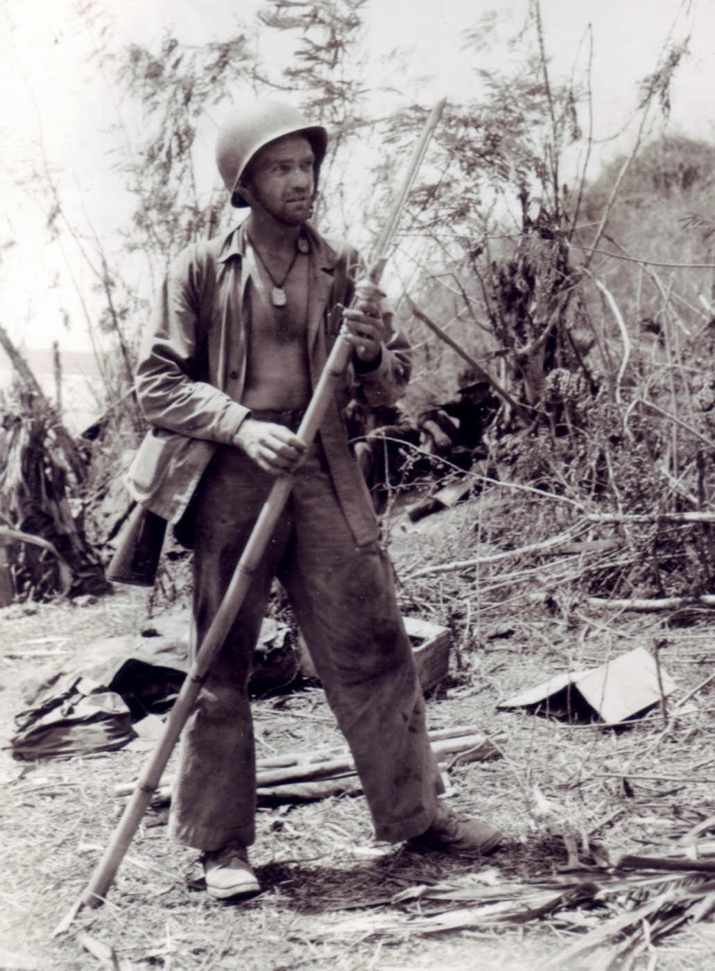 In this image, a U.S. Marine examines a Japanese spear made from a bamboo pole and a bayonet. The weapon was recovered on Saipan, Mariana Islands during World War II.