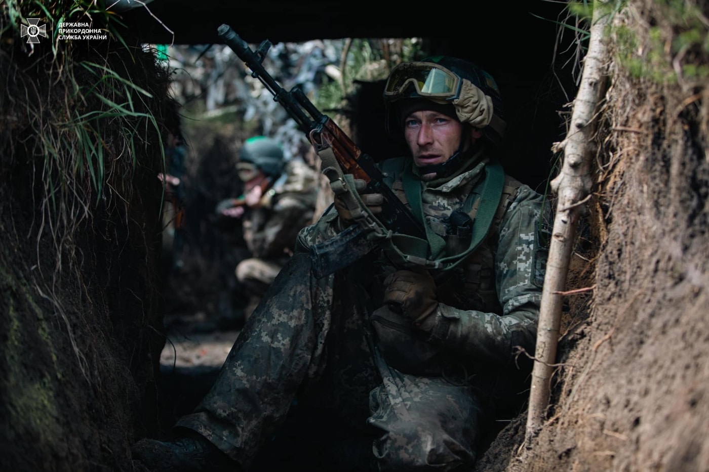In this photo, we see a Ukrainian soldier in camouflage and carrying an AK-74 assault rifle in a trench near the perimeter of the airport. The airport was captured by the Russian forces, but was liberated by Ukraine. 