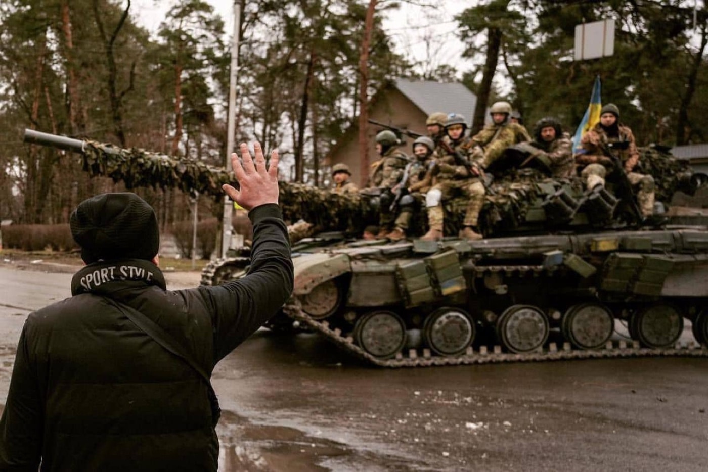 This photograph taken during the 2022 Russian invasion of Ukraine shows a Ukrainian citizen waving to his country's troops after they defeated Russian airborne forces. Earlier in the day, soldiers celebrating the victory did take control of the city. 