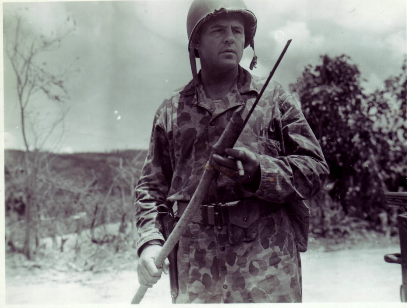 A U. S. Marine in early camouflage inspects a crude Japanese banzai spear recovered on Saipan.