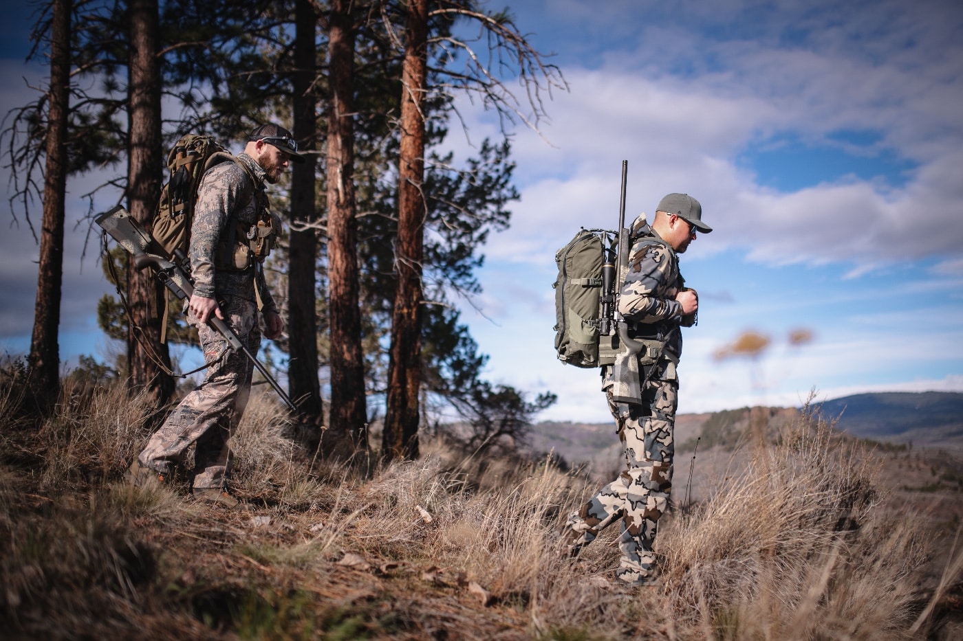 In this photo we see a pair of hunters wearing camouflage clothing as they carry Springfield Waypoint long-action rifles into the field for a hunt.