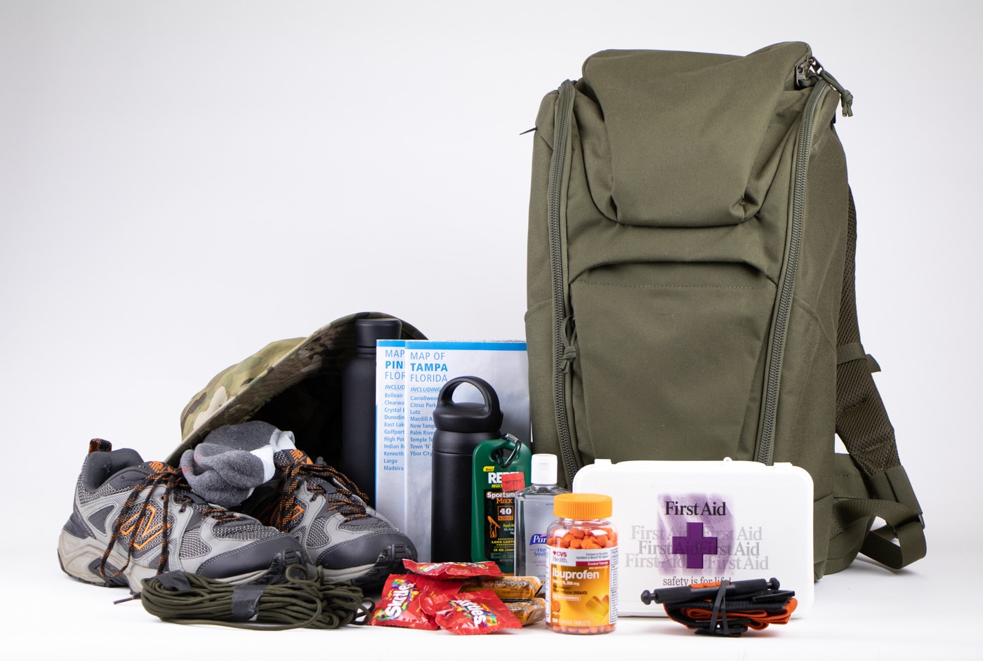Shown here is the Tasmanian Tiger TT TAC Modular SW Pack 25 review as a get home bag. It is complete with hiking shoes, snacks, a first aid kit, water and bug repellant.