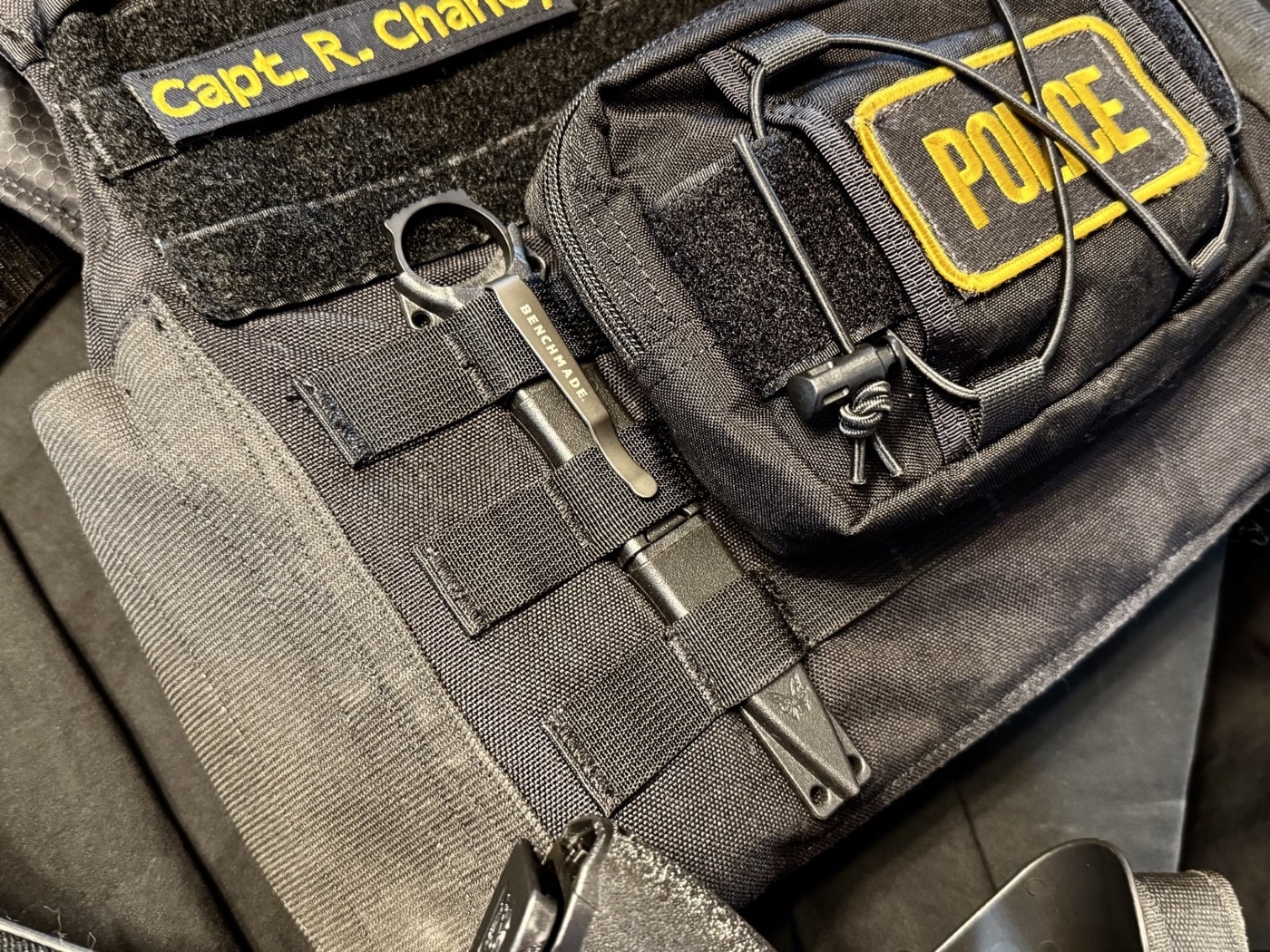 The dagger is shown lying flat on a plate carrier, ring exposed and sheath tucked into webbing. This is a staged carry position, exactly as intended by the designer. Everything about the knife’s size and shape is tuned for this type of integration. It won’t snag or bounce around when you move. It stays in place until it’s needed, and when it’s needed, it comes out fast. That’s the point of the system.
