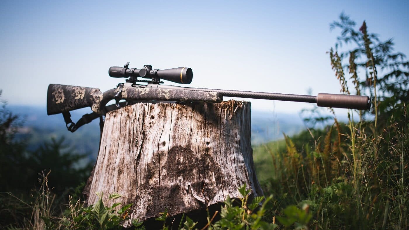 Shooter aiming downrange with a suppressed bolt-action rifle on a bipod. The scene is calm and focused. The image helps show that suppressors do not hinder precision shooting and can be used in accuracy-focused setups. Supports the argument that suppressors don’t negatively impact performance.