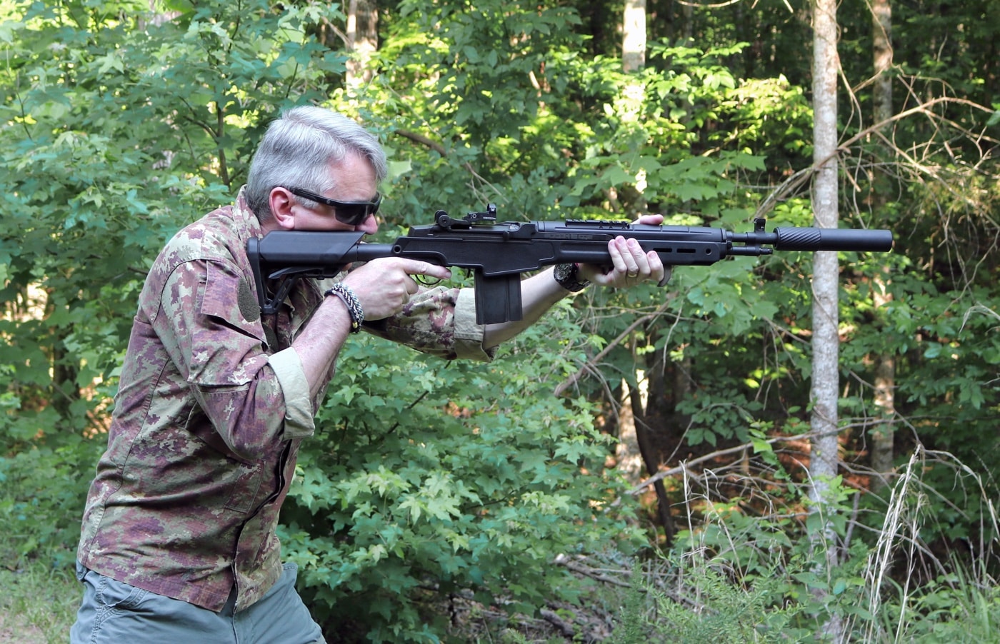 Side view of a shooter practicing rapid fire with a suppressed M1A. The shooter is tracking the sights smoothly with minimal muzzle movement. The image emphasizes how suppressors reduce blast and allow for better shot control. Supports claims of improved shootability.