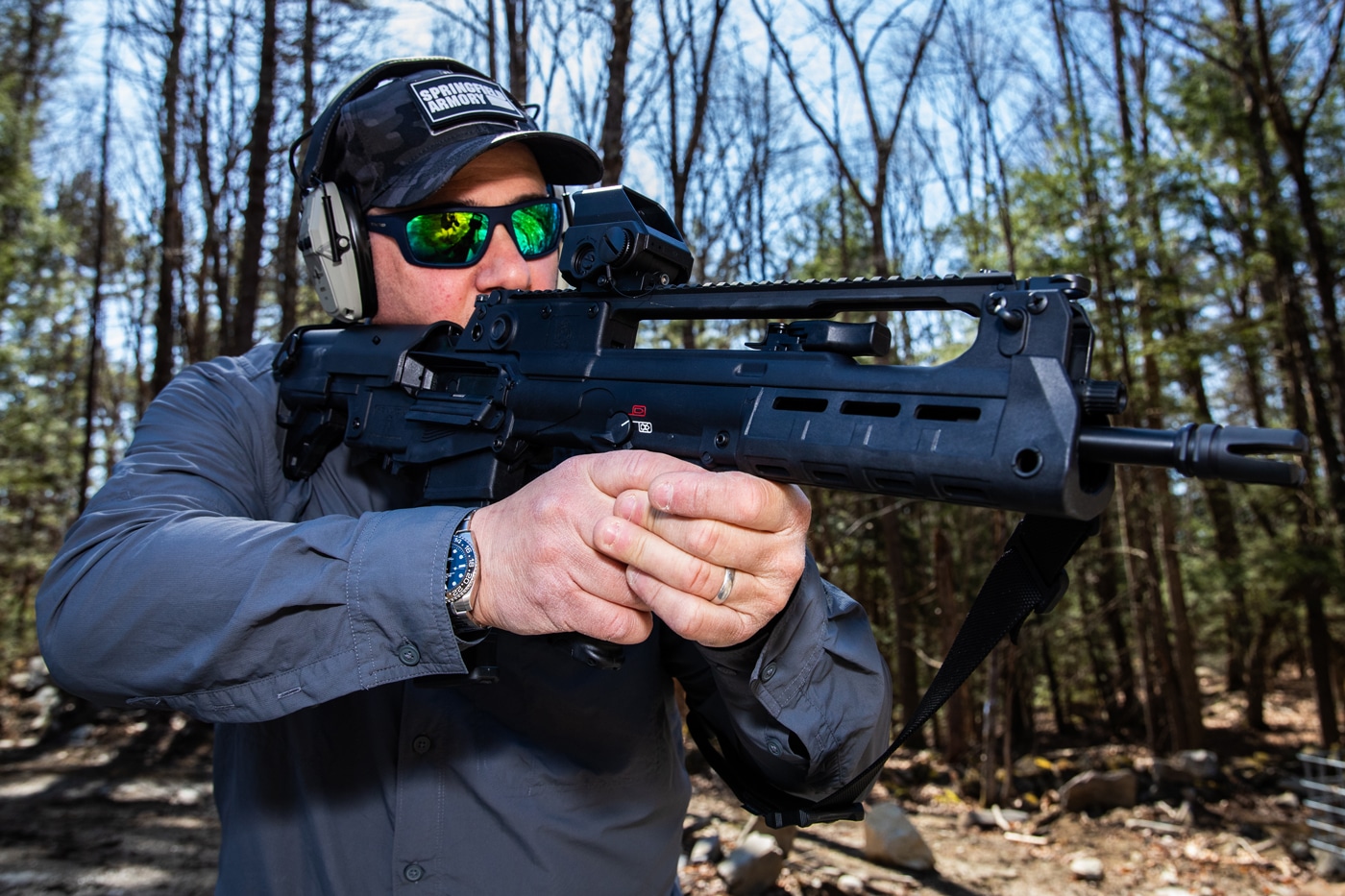 A shooter using the Mepro Tru-Vision SR from a prone position at a range. The optic is mounted on a Springfield Hellion rifle. The red dot is used to acquire targets quickly while maintaining a low shooting profile. Shooter demonstrates practical field use. This sight is made for real-world tactical shooting.