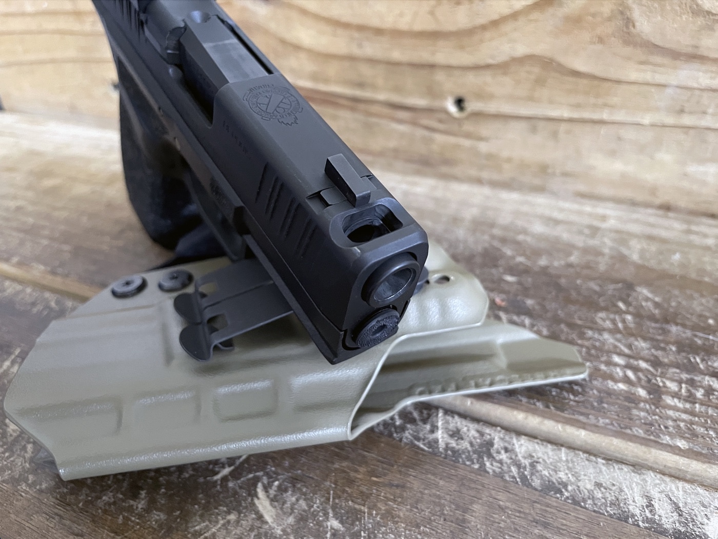 Close-up of a handgun barrel showing both the bore and a small compensator port. The photo is taken from an oblique angle to highlight both features. This helps illustrate the comparison between a standard barrel opening and the additional port. It supports the point that concerns about debris entering the port often ignore that the bore is also exposed. Relevant for discussing maintenance concerns with comped pistols.