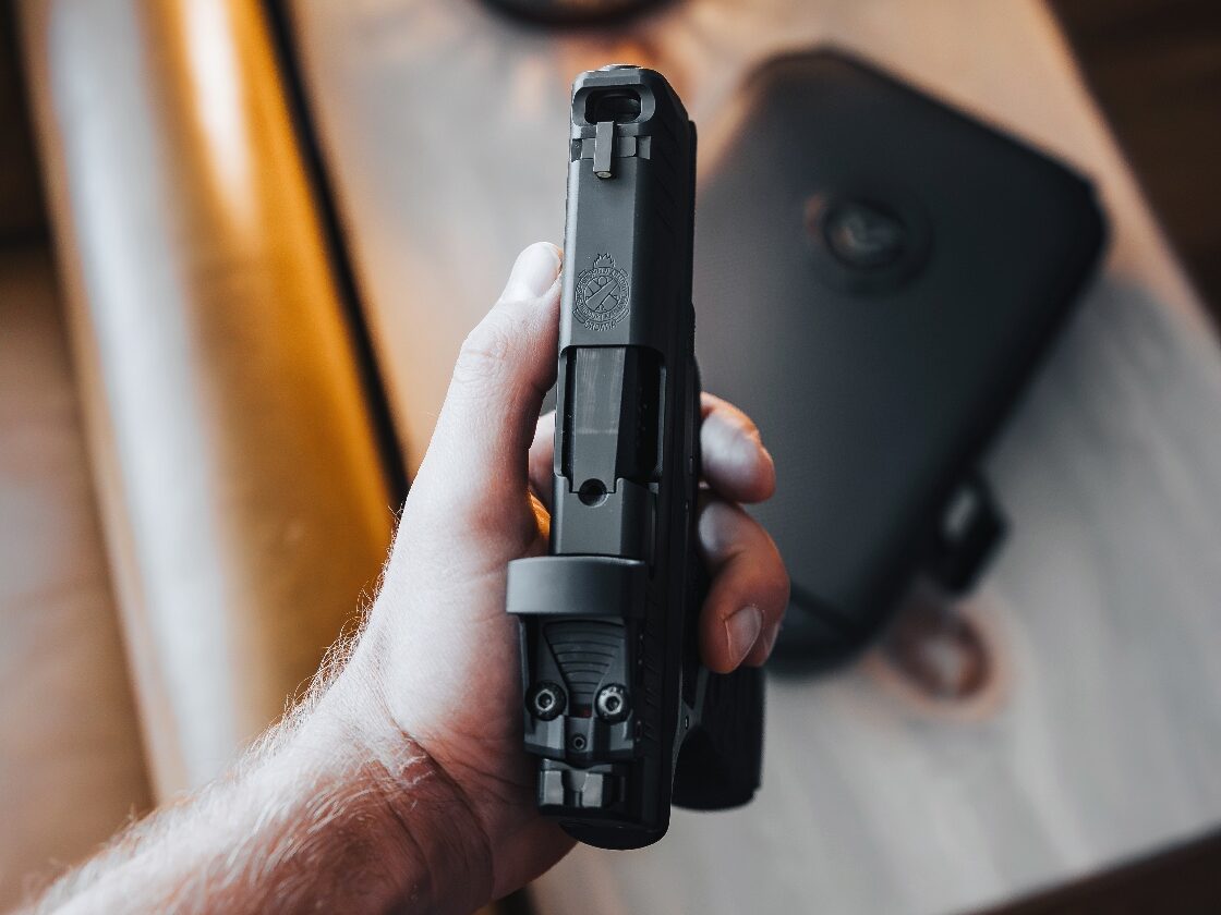 Close-up photo of a ported pistol barrel and slide. The image shows a single port on top, located just in front of the front sight. This is a built-in compensator design, not an aftermarket add-on. Gas vents through the port when the gun is fired to reduce muzzle rise and perceived recoil. The photo helps explain how compensators work in ported pistol designs. It’s relevant to the discussion of ported pistol myths and how comps affect performance in defensive handguns.