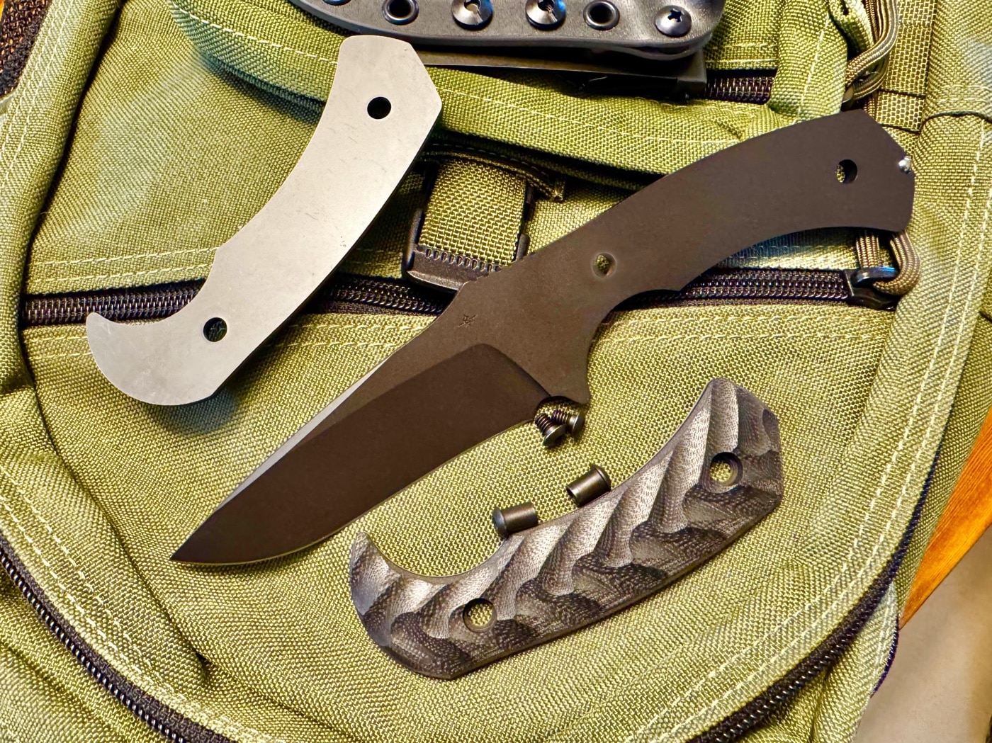 Backside view of the Toor Knives Mullet S showing the full tang extending through the handle. The tang is 3/16-inch thick CPM M4 tool steel and features a tungsten carbide breacher ball at the end. This robust design adds weight and durability for hard use tasks. The handle scales are bolted directly to the tang without relief cuts. Ideal for users who prioritize strength over weight savings.