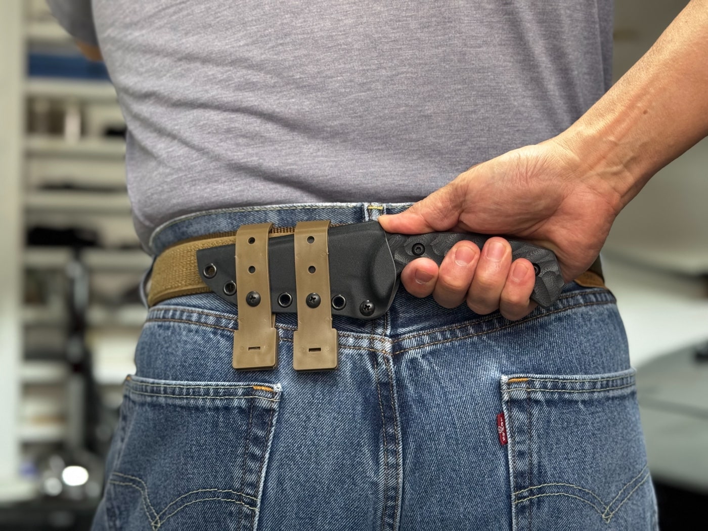 Side view of the Toor Mullet S mounted horizontally on a belt for scout carry. The sheath is secured using MALICE clips attached to MOLLE webbing. The knife sits flush against the back and is easily concealed under a shirt. This carry position offers quick access without printing. Suitable for tactical or concealed fixed blade use.