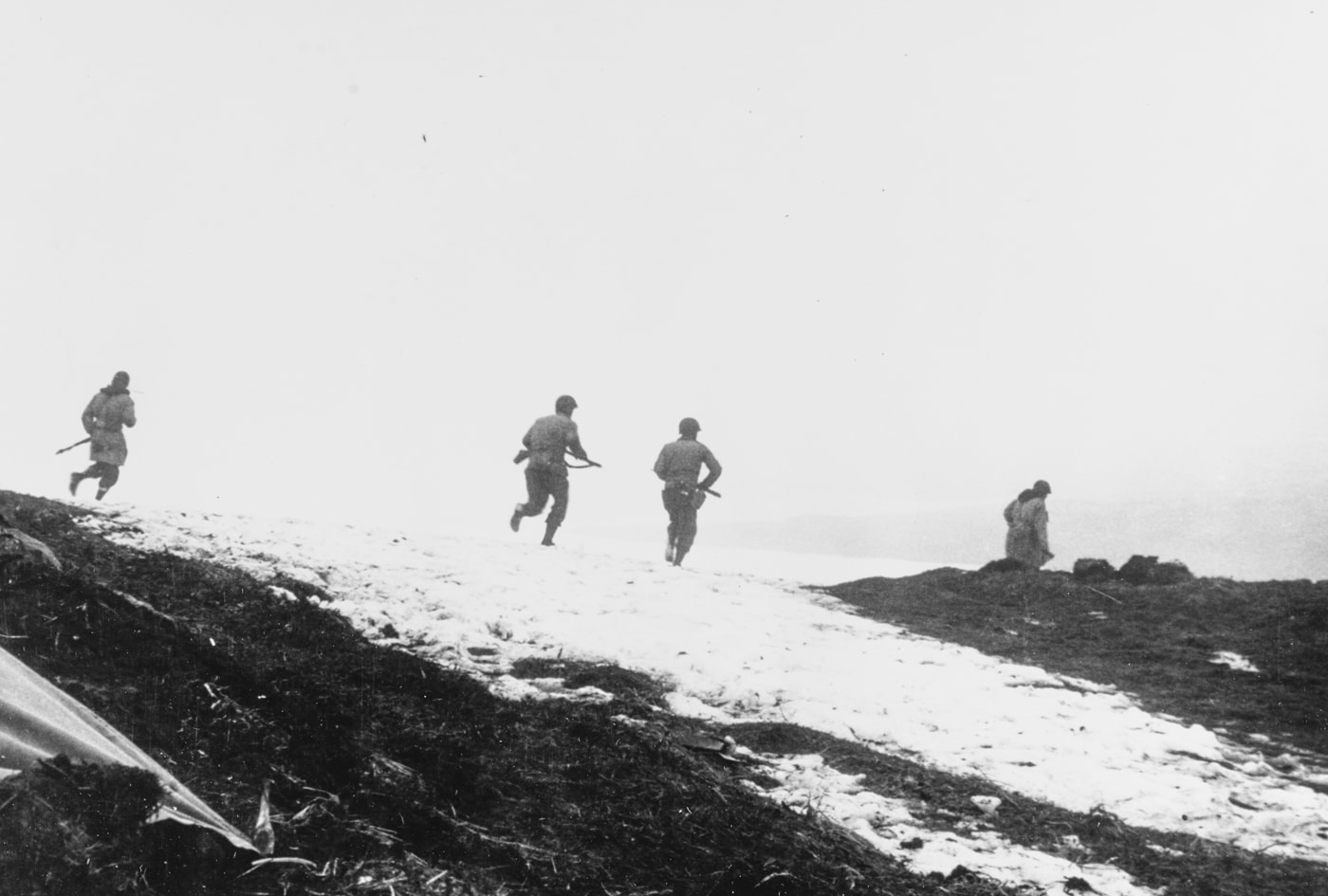 soldiers advance along a hilltop on Attu