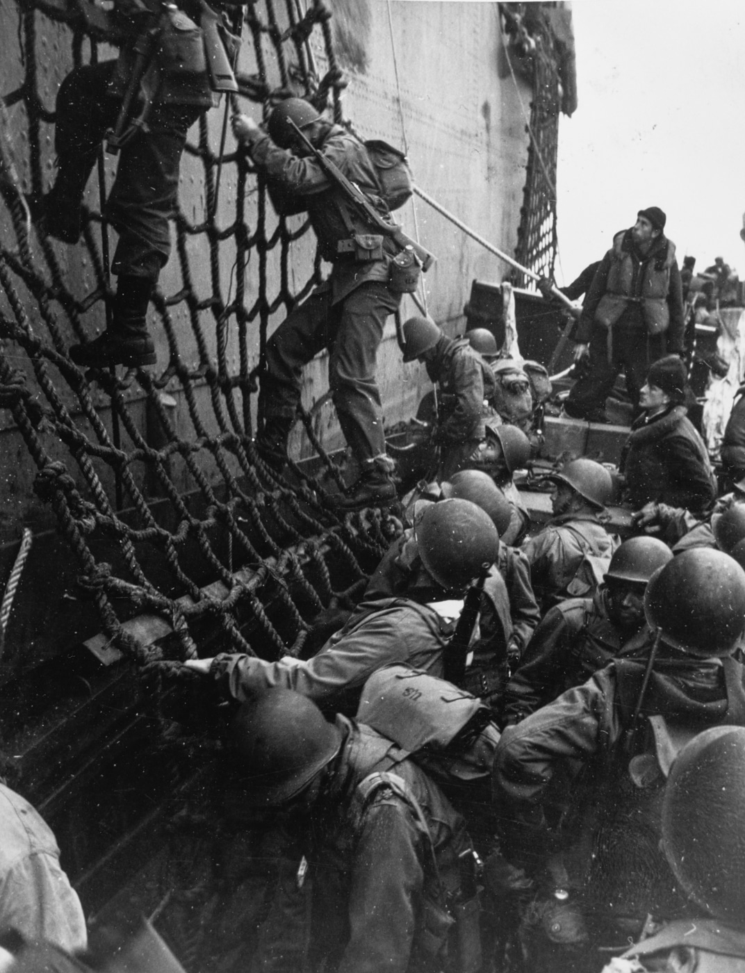 soldiers climb down cargo nets to landing craft to invade Attu